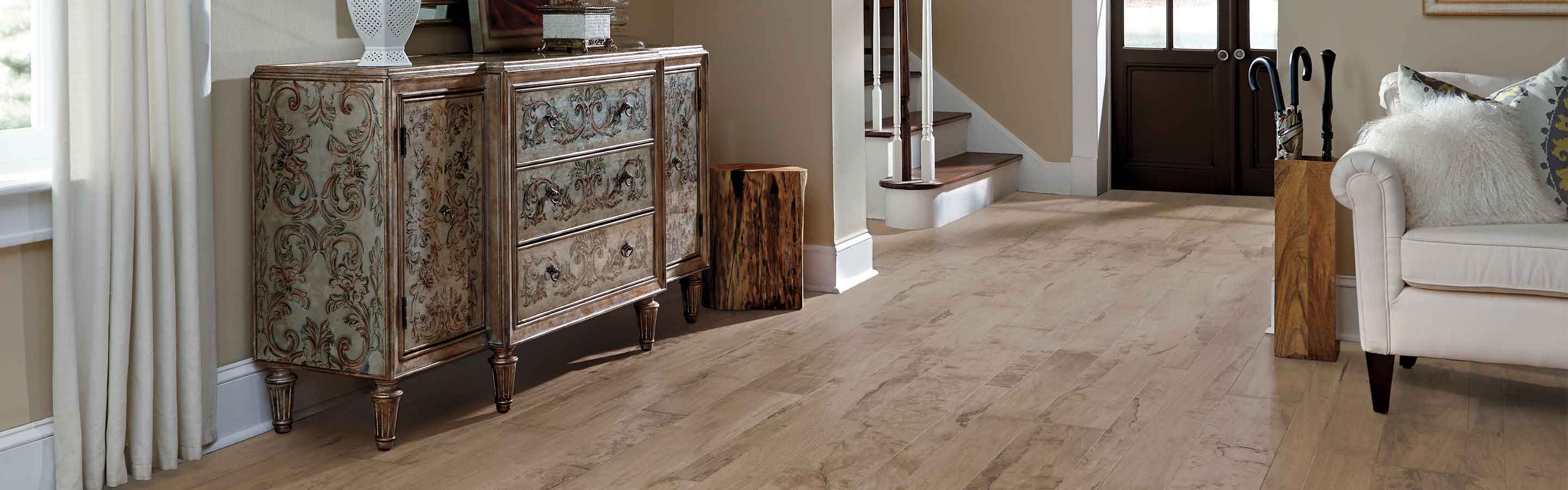 hardwood flooring in living room entryway with neutral colorway, white couch and vintage side table