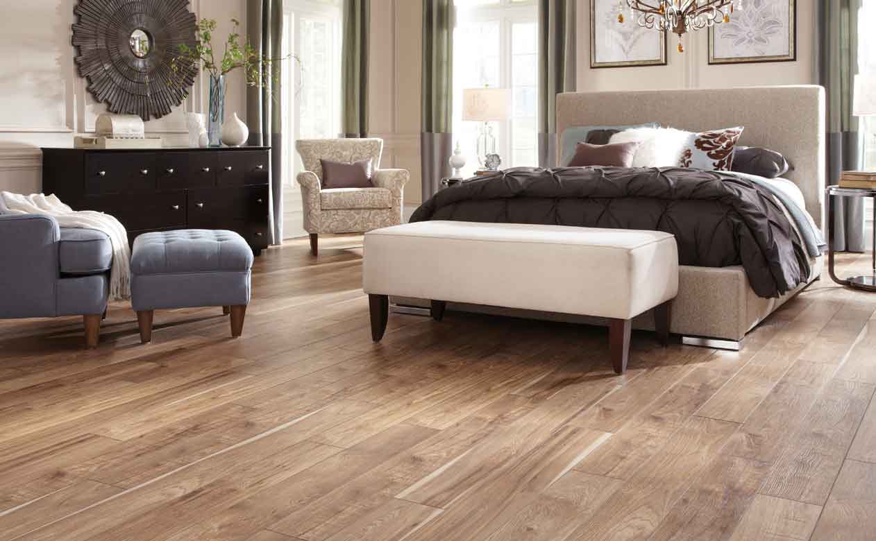 A cozy bedroom with wood-look tile flooring, complemented by a variety of furniture in different colors